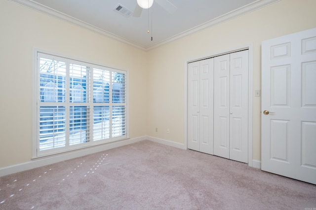 unfurnished bedroom featuring baseboards, visible vents, crown molding, and carpet flooring