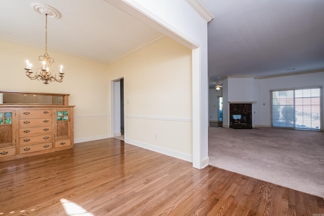 unfurnished dining area featuring ornamental molding, a fireplace, wood finished floors, and baseboards