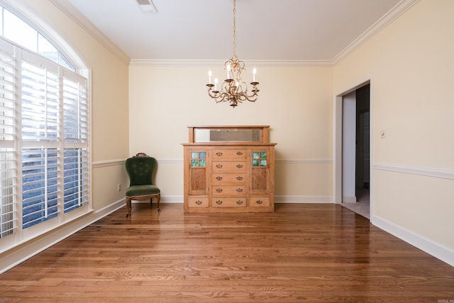 unfurnished room with an inviting chandelier, baseboards, ornamental molding, and wood finished floors