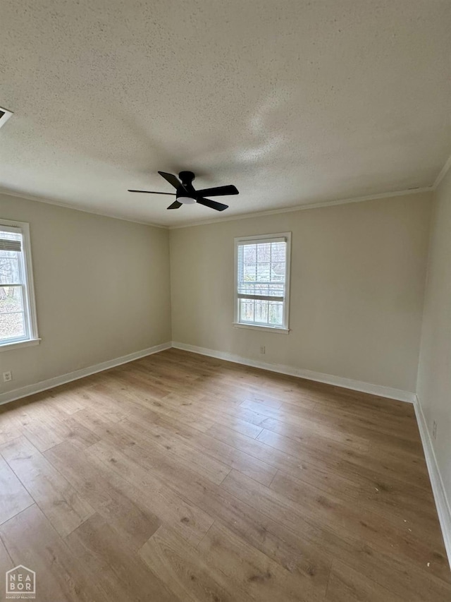 spare room featuring a wealth of natural light, ceiling fan, crown molding, and wood finished floors