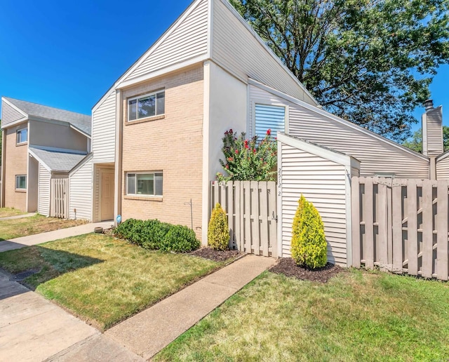 view of home's exterior with fence, a lawn, and brick siding