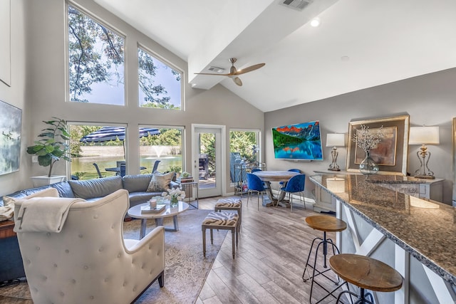 living area with a healthy amount of sunlight, a ceiling fan, high vaulted ceiling, and wood finished floors