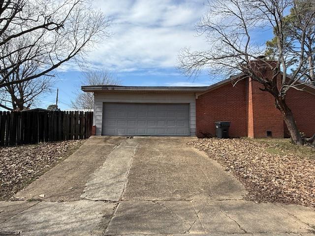 garage featuring fence and concrete driveway