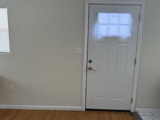 entryway with a textured wall, baseboards, and wood finished floors