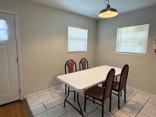 dining space with a textured ceiling and baseboards