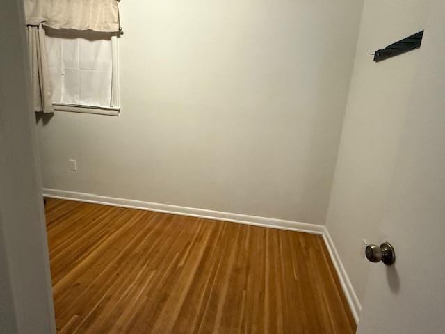 spare room featuring baseboards and wood finished floors