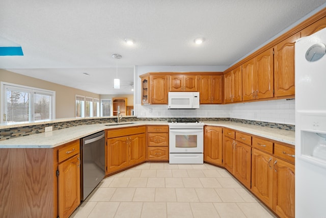 kitchen featuring white appliances, decorative backsplash, brown cabinetry, a peninsula, and a sink