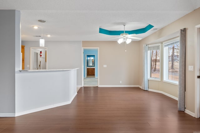 unfurnished room with dark wood-style floors, a textured ceiling, baseboards, and a ceiling fan