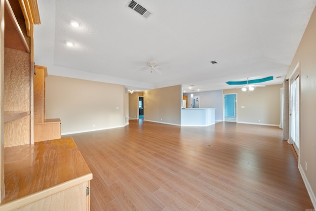 unfurnished living room with light wood-type flooring, baseboards, visible vents, and a ceiling fan