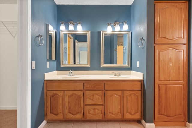 full bathroom with double vanity, tile patterned flooring, and a sink