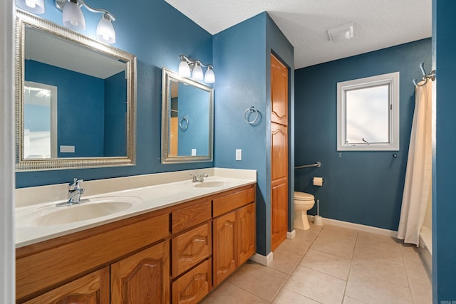 full bath featuring toilet, double vanity, a sink, and tile patterned floors