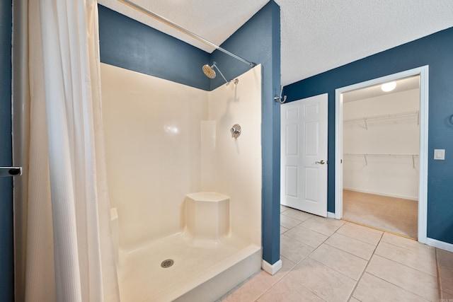 full bathroom featuring tile patterned flooring, baseboards, a shower stall, and a textured ceiling