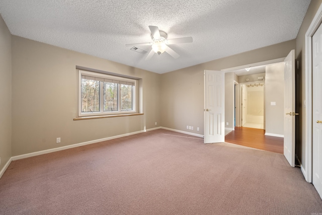 carpeted empty room featuring ceiling fan, a textured ceiling, visible vents, and baseboards