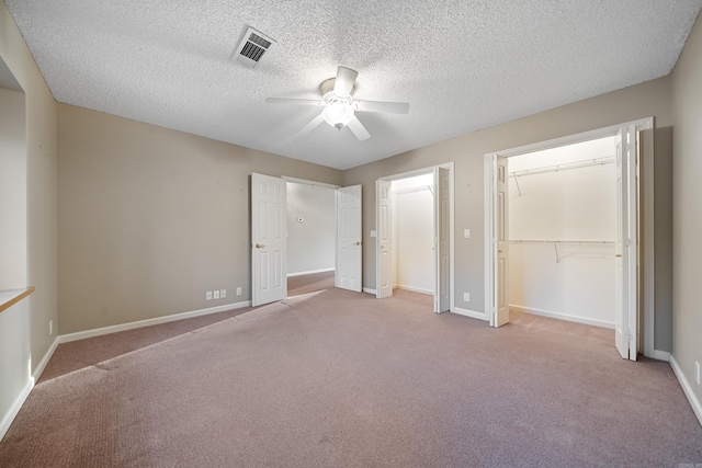 unfurnished bedroom with ceiling fan, a textured ceiling, carpet floors, visible vents, and baseboards