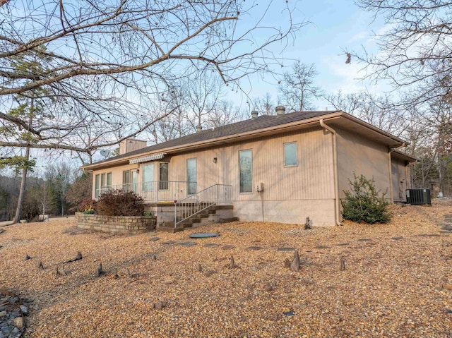 back of property with central AC and a chimney