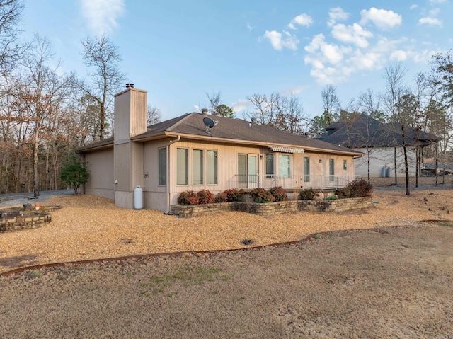 rear view of property featuring a shingled roof and a chimney