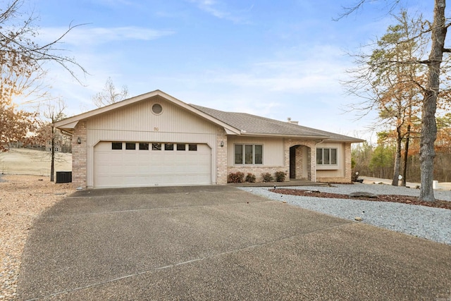 view of front of home featuring a garage, concrete driveway, brick siding, and roof with shingles