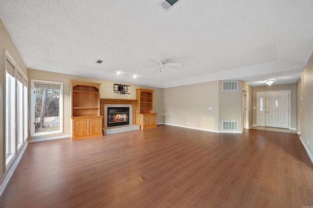 unfurnished living room featuring visible vents, a fireplace, and wood finished floors