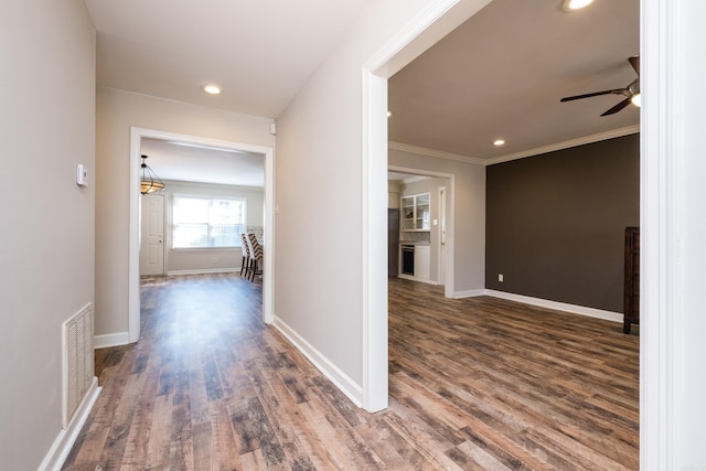 hall featuring visible vents, baseboards, wood finished floors, crown molding, and recessed lighting