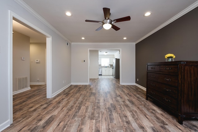 spare room featuring baseboards, visible vents, wood finished floors, crown molding, and recessed lighting