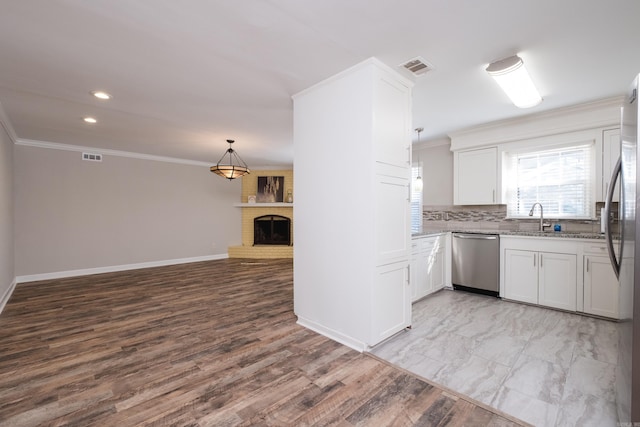 kitchen featuring stainless steel appliances, ornamental molding, and a brick fireplace