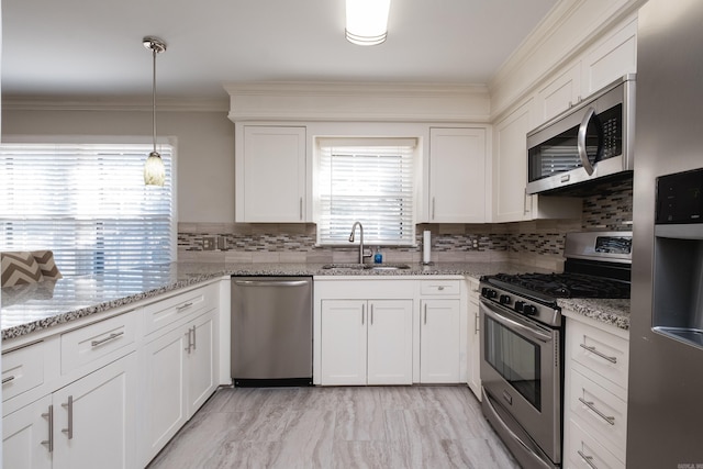 kitchen with crown molding, white cabinetry, stainless steel appliances, and a sink