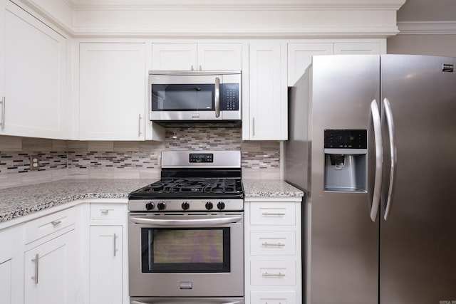 kitchen with tasteful backsplash, ornamental molding, light stone countertops, stainless steel appliances, and white cabinetry