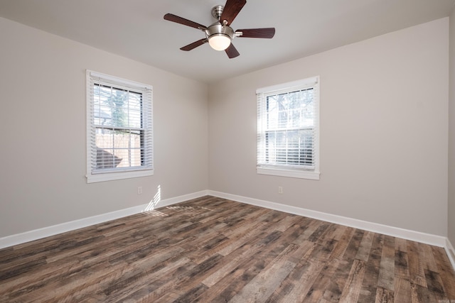 unfurnished room with dark wood-style flooring, a wealth of natural light, and baseboards