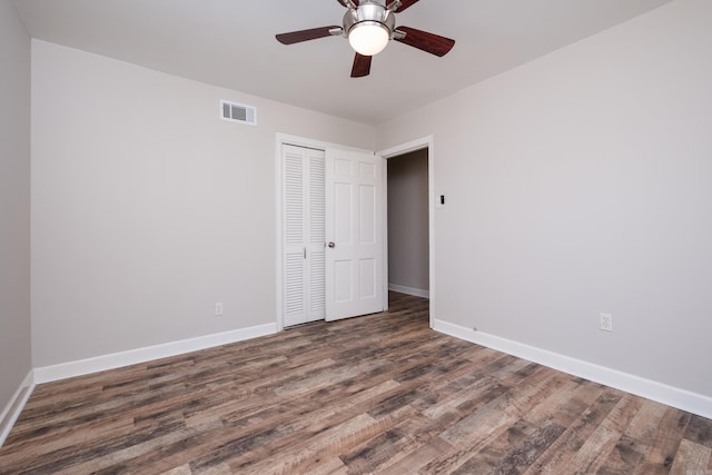 unfurnished bedroom with ceiling fan, wood finished floors, visible vents, baseboards, and a closet