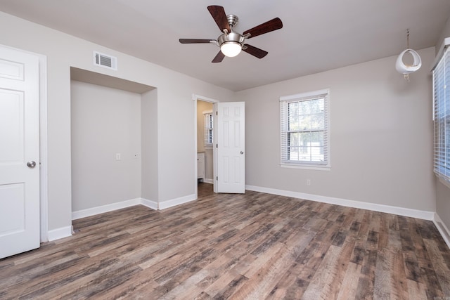 unfurnished bedroom featuring ceiling fan, wood finished floors, visible vents, and baseboards