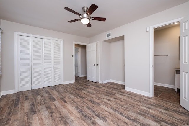 unfurnished bedroom with wood finished floors, a ceiling fan, visible vents, baseboards, and a closet