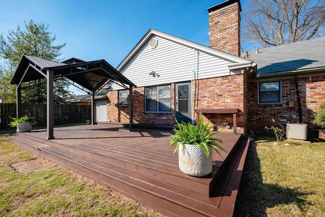 wooden deck with a gazebo, a lawn, and fence