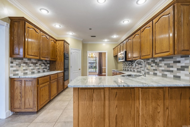 kitchen with brown cabinetry, stainless steel microwave, light stone counters, a peninsula, and a sink