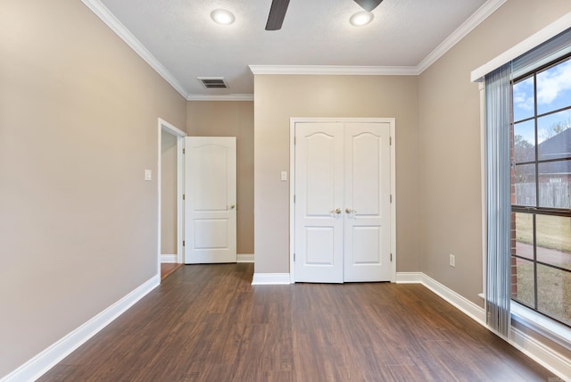 unfurnished bedroom with a closet, visible vents, ornamental molding, wood finished floors, and baseboards