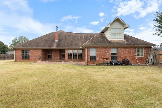 rear view of house featuring a patio, brick siding, a lawn, and fence