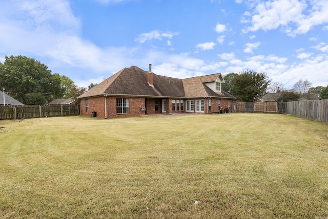 back of property featuring brick siding, a lawn, and a fenced backyard