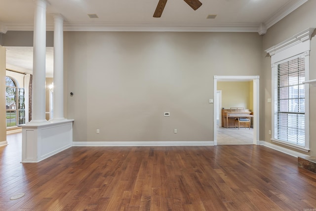 spare room with ceiling fan, wood finished floors, baseboards, decorative columns, and crown molding