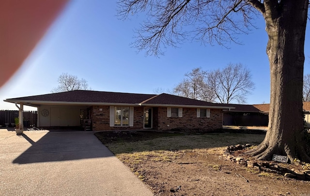 ranch-style home featuring fence, an attached carport, concrete driveway, and brick siding