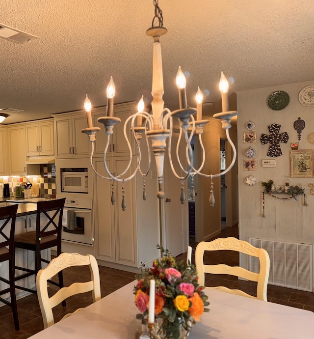 dining room with dark tile patterned flooring, visible vents, and a textured ceiling