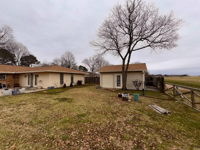 back of property with an outbuilding, a patio area, a yard, and a fenced backyard