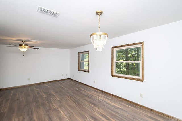 empty room featuring a wealth of natural light, dark wood-type flooring, visible vents, and baseboards