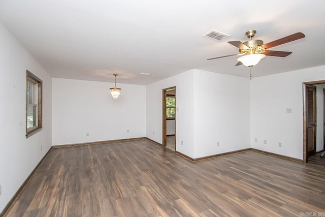 spare room with a ceiling fan, visible vents, baseboards, and wood finished floors