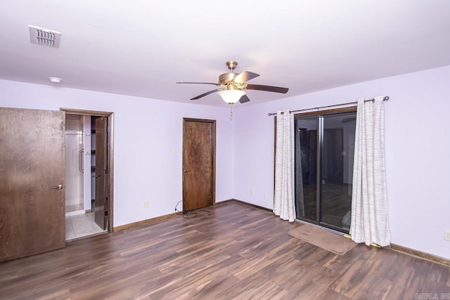 spare room featuring baseboards, visible vents, ceiling fan, and wood finished floors