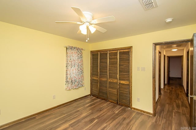 unfurnished bedroom featuring baseboards, visible vents, a ceiling fan, dark wood finished floors, and a closet