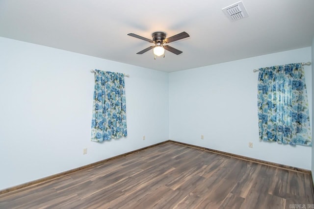 empty room with baseboards, ceiling fan, visible vents, and dark wood-style flooring