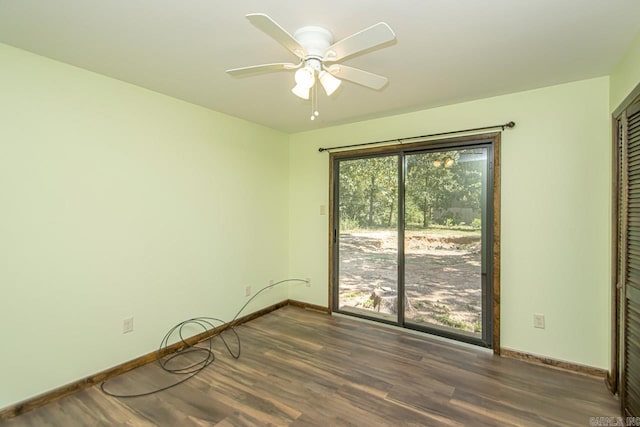 spare room featuring ceiling fan, dark wood finished floors, and baseboards