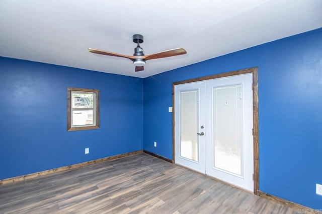 empty room with ceiling fan, wood finished floors, a wealth of natural light, and baseboards