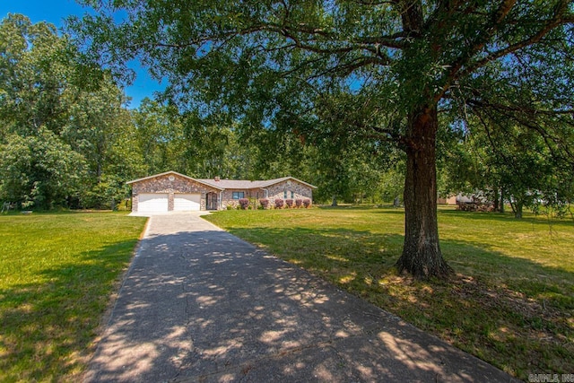 view of front of home featuring a front yard, stone siding, driveway, and an attached garage