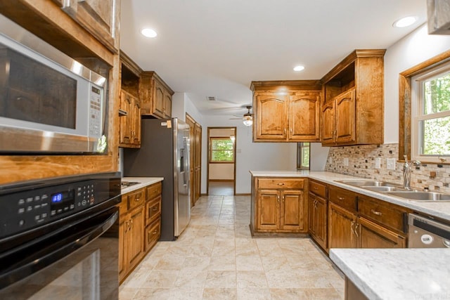 kitchen with appliances with stainless steel finishes, a healthy amount of sunlight, a sink, and brown cabinets