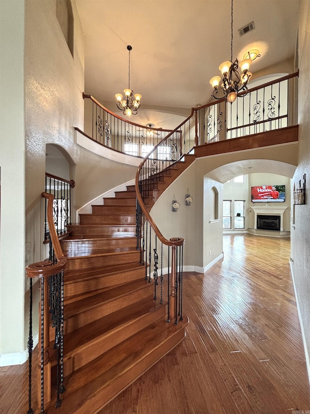 stairway with visible vents, a chandelier, arched walkways, and hardwood / wood-style floors